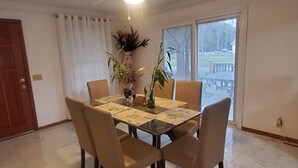 Un comedor con una mesa de vidrio, cuatro sillas y dos plantas en macetas.