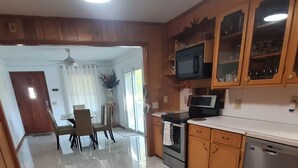 Una cocina con suelo de mármol, armarios de madera, microondas, horno y lavavajillas.