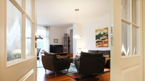 Uma sala de estar com sofá, televisão e um quadro na parede.