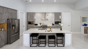 A modern kitchen with a central island, stainless steel appliances, and pendant lighting.
