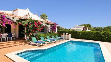 Relax by the clear pool surrounded by lounge chairs and lush greenery.