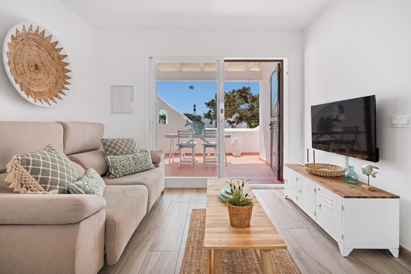 A living room with a sofa, TV, and a view to an outdoor patio.