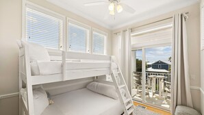 Habitación con literas y vistas a una casa a través de una puerta corrediza de vidrio.