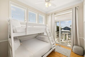 A bunk bed room with a view of a house through a sliding glass door.