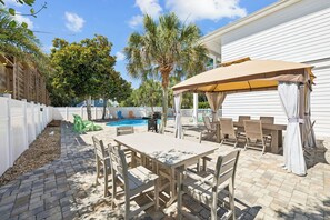 Ein Patio mit Pool, Gartenmöbeln und einer überdachten Sitzgelegenheit.