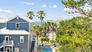 Un barrio residencial con una casa azul, una piscina y vistas al océano.