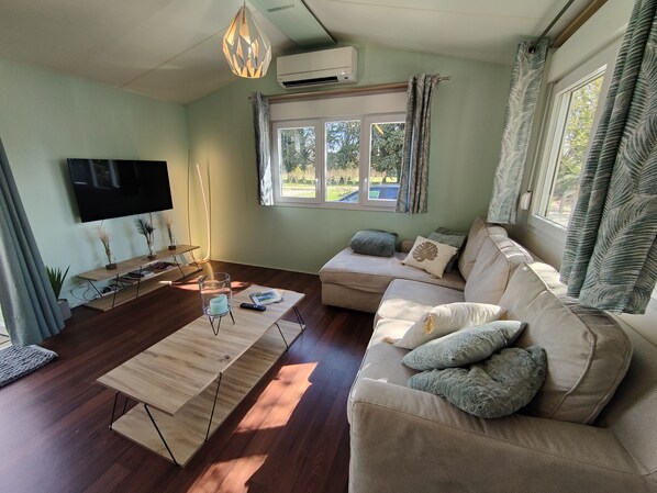 A living room with a sofa, a coffee table, a TV, and a window with curtains.
