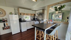 Une cuisine moderne avec des meubles blancs, un plan de travail noir et des tabourets en bois.