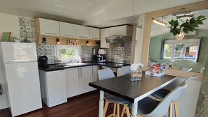 Une cuisine moderne avec des meubles blancs, un plan de travail noir et une table à manger en bois, accompagnée de chaises.