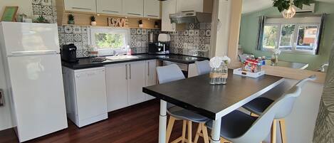 A modern kitchen with white cabinets, a black countertop, and a wooden dining table with chairs.