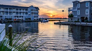 A waterfront hotel with a boat dock, multiple balconies, and a sunset view. - Canal Front Views, Boat Dock, Kayaks, 10" Walk to the Beach, Free Activities inc. Golf at Bear Trap. (Fenwick Island)