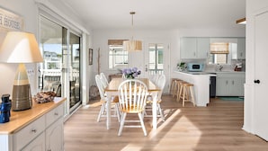 A spacious kitchen with white cabinetry, a dining area with a wooden table and chairs, and a view of the outside. - Canal Front Views, Boat Dock, Kayaks, 10" Walk to the Beach, Free Activities inc. Golf at Bear Trap. (Fenwick Island)
