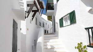 A narrow, white-walled alleyway with steps leading to a building entrance, green shutters, and a potted plant. - 3min. Walk to the beach, Villa Bini  Perla, sea view, sunny, quiet location (Binibequer)