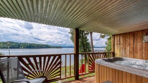 A wooden deck with a hot tub, a chair, and a view of a lake.