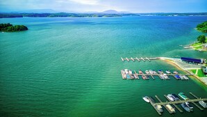 An aerial view of a marina with boats docked, surrounded by water and greenery.