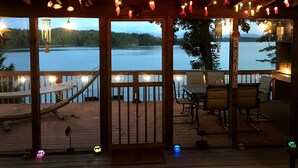 A wooden deck with a view of a lake, outdoor seating, and a 'No Smoking' sign.