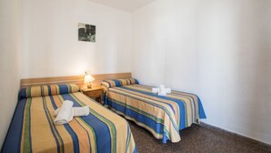 A hotel room with two beds, each with striped bedding, a nightstand with a lamp, and a small picture on the wall. - AQUARIUM II 2-3 (benidorm)