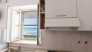 Une cuisine avec une fenêtre, une cuisinière à gaz et un évier.