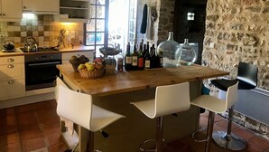 A kitchen with a stone wall, wooden counter, and two white bar stools. - calm and nature, with private pool (vindrac-alayrac)