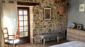 A bedroom with a stone wall, a wooden bench, a bed, a dresser, and a window with a view of greenery. - calm and nature, with private pool (vindrac-alayrac)