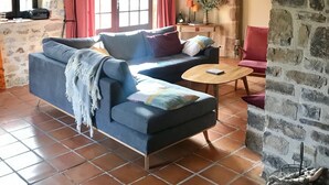 A cozy living room with a blue sofa, a wooden coffee table, and a stone wall. - calm and nature, with private pool (vindrac-alayrac)