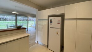 A modern kitchen with white cabinets, a built-in refrigerator, and a large window overlooking a grassy area. - Fantastico Duplex Con Jardin y Piscina (Villa San Lorenzo)