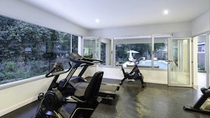 A modern gym with treadmills and exercise bikes, large windows offering views of the outdoors. - Fantastico Duplex Con Jardin y Piscina (Villa San Lorenzo)