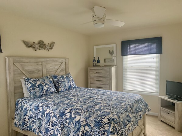 A bedroom with a bed, dresser, TV stand, and a ceiling fan. - Completely Refurbished, Modern Accommodations, and One Block to the Beach! (Wildwood)