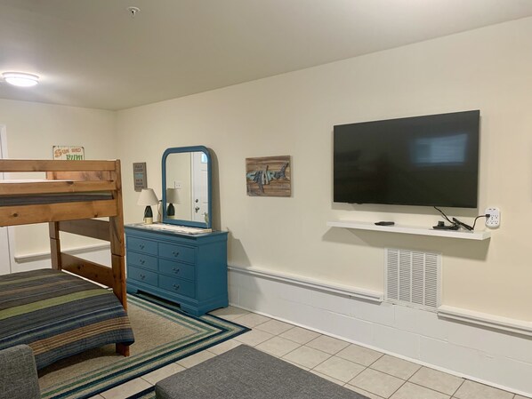 A bedroom with a bunk bed, a dresser, a TV, and a small shelf. - Completely Refurbished, Modern Accommodations, and One Block to the Beach! (Wildwood)