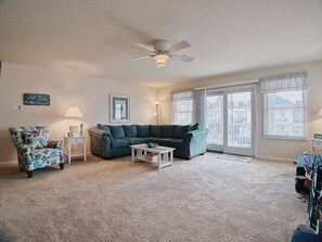 A living room with a dark green sofa, a floral armchair, a white coffee table, and a ceiling fan. - Completely Refurbished, Modern Accommodations, and One Block to the Beach! (Wildwood)