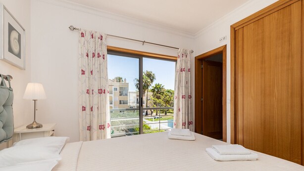 Une chambre d’hôtel avec un lit, une table de chevet avec une lampe, une fenêtre avec des rideaux et une vue sur l’extérieur.