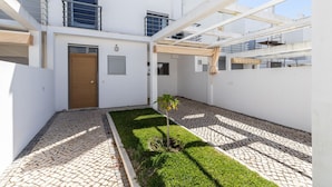 Un bâtiment moderne doté d’une cour intérieure, d’une porte en bois et d’un petit jardin.