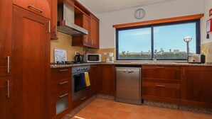 Una cocina con armarios de madera, microondas, lavavajillas y una ventana con vistas.