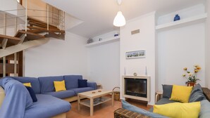 Una sala de estar moderna con un sofá azul, una mesa de centro de madera, una chimenea y una escalera.