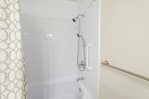 Un bagno con doccia rivestita in piastrelle bianche, una vasca e un water.