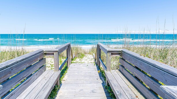 A wooden boardwalk leading to a beach with clear blue water and distant horizon. - Beaulieu-Sur-Duck - Sanderling, Ocean View, Steps to Direct Boardwalk, Pets OK, Flex Stays (Duck)