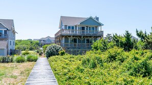A beachfront property with a wooden deck leading to a house with a balcony. - Beaulieu-Sur-Duck - Sanderling, Ocean View, Steps to Direct Boardwalk, Pets OK, Flex Stays (Duck)
