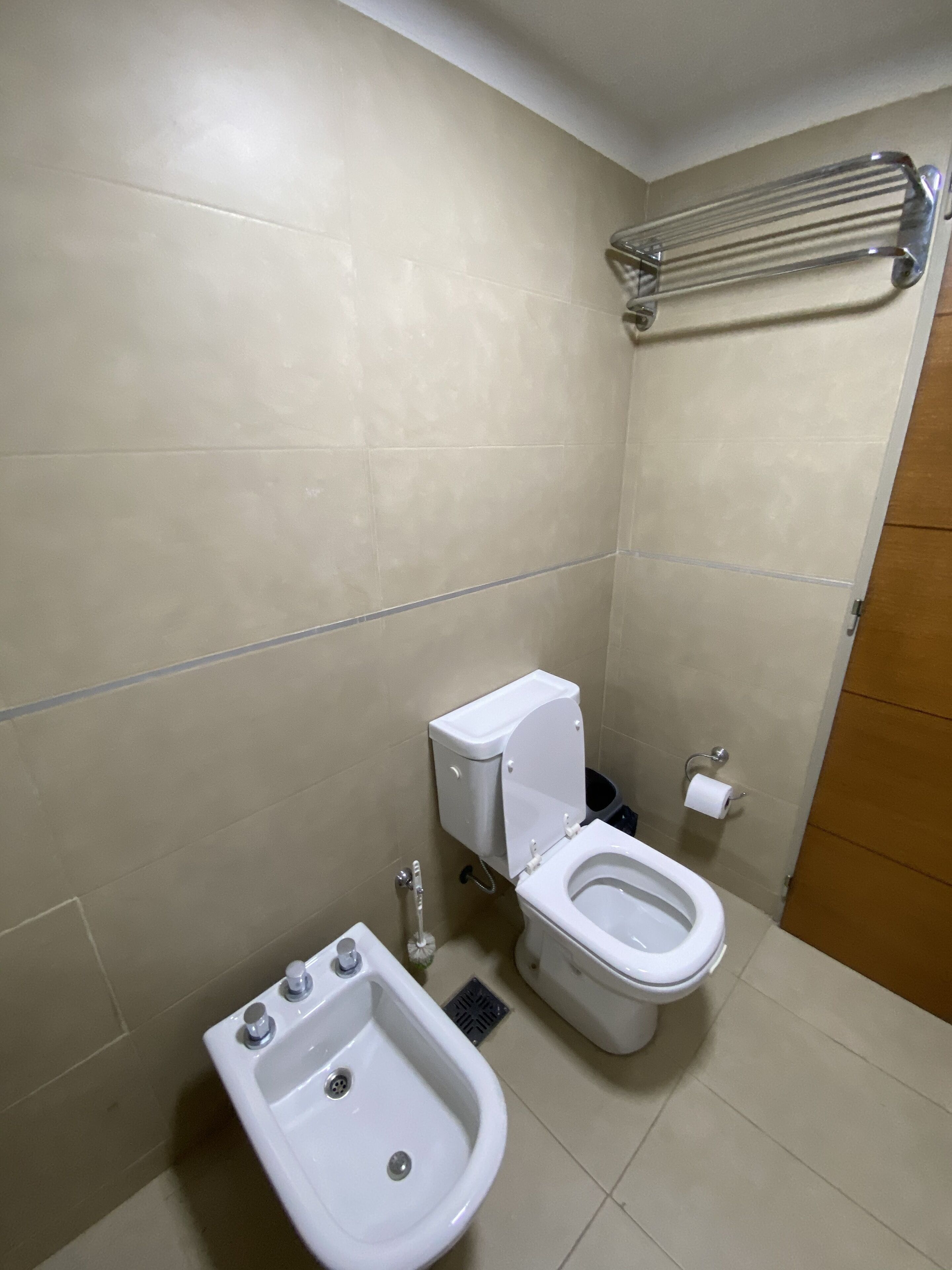 A small, clean bathroom with a toilet, bidet, and a towel rack.