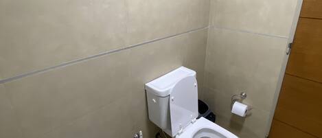 A small, clean bathroom with a toilet, bidet, and a towel rack.
