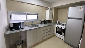 A compact kitchen with a microwave, sink, stove, and refrigerator. - Depto Con Inmejorable Ubicación (Salta)