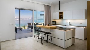 Eine moderne Küche mit einer großen Kochinsel, Barhocker und Meerblick.