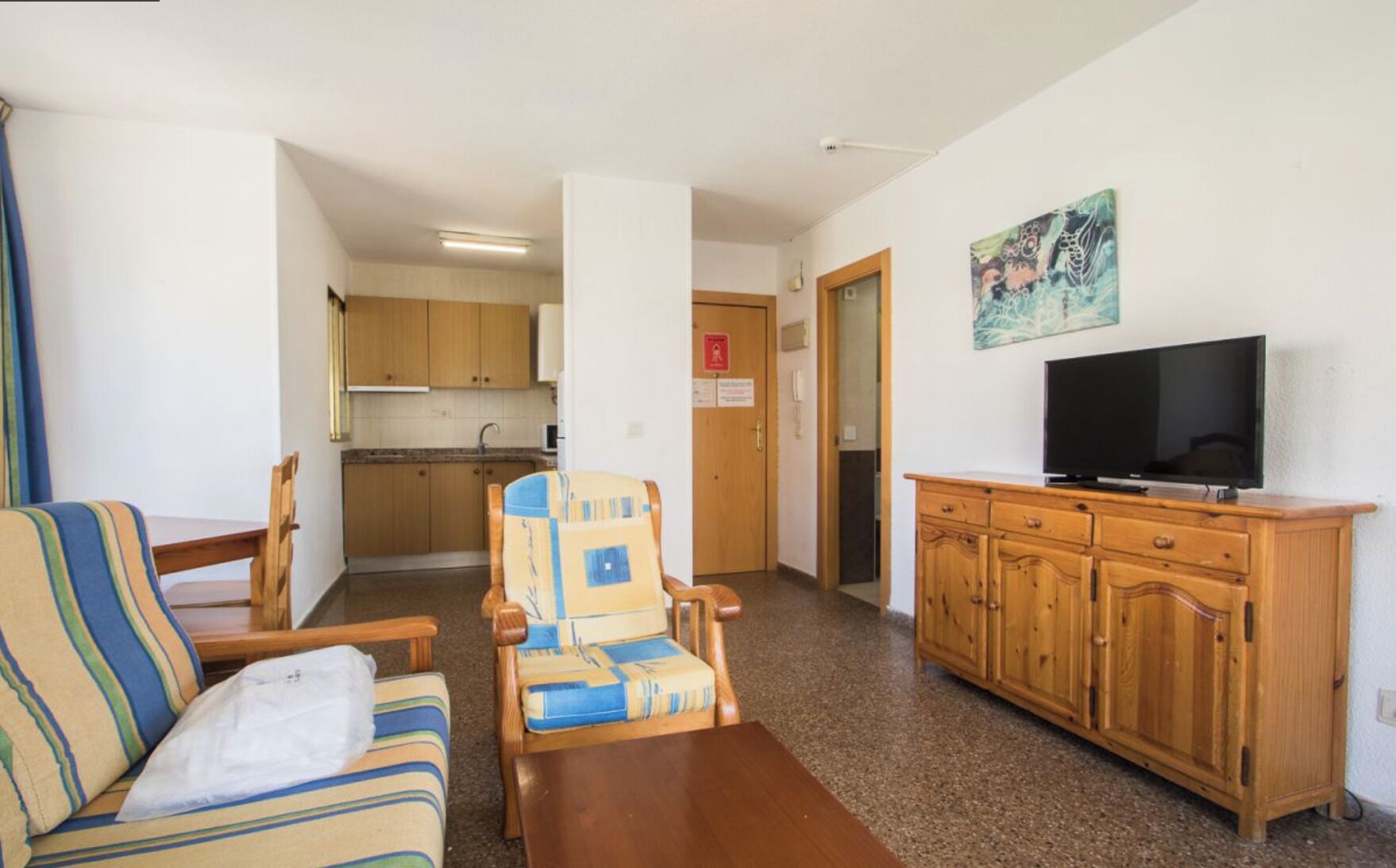 Una sala de estar con sofá, sillón, aparador de madera y televisor.