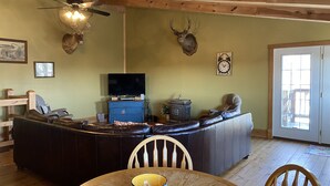 Una sala de estar acogedora con techo de madera, chimenea, televisor y adornos de asta de ciervo en la pared.