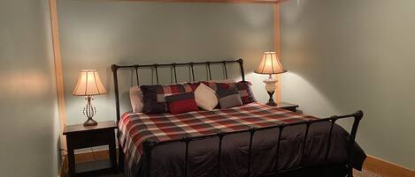 A bedroom with a bed, two bedside tables, a ceiling fan, and two lamps.