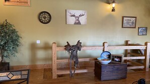 Un interior rústico con muebles de madera, un reloj y decoración en la pared, incluyendo un cuadro de un ciervo.