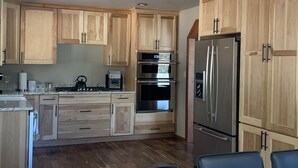 A kitchen with wooden cabinets, stainless steel appliances, and a skylight. - 6 acres, Hot tub, Pikes Peak ⛰ View, Sleeps 8 (Woodland Park)
