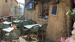 Un café al aire libre con mesas y sillas, un letrero que dice "saladerie" y un rústico edificio de piedra.