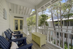 A covered porch with wooden benches and a yellow chest of drawers.