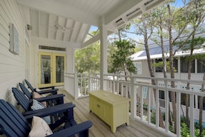 A covered porch with wooden benches and a yellow chest of drawers.