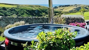 A hot tub with a stone wall and greenery in the background. - Sea views just yards from restaurants, pubs & shops. Sleeps 16-18, 8 x en-suite. (Tintagel)